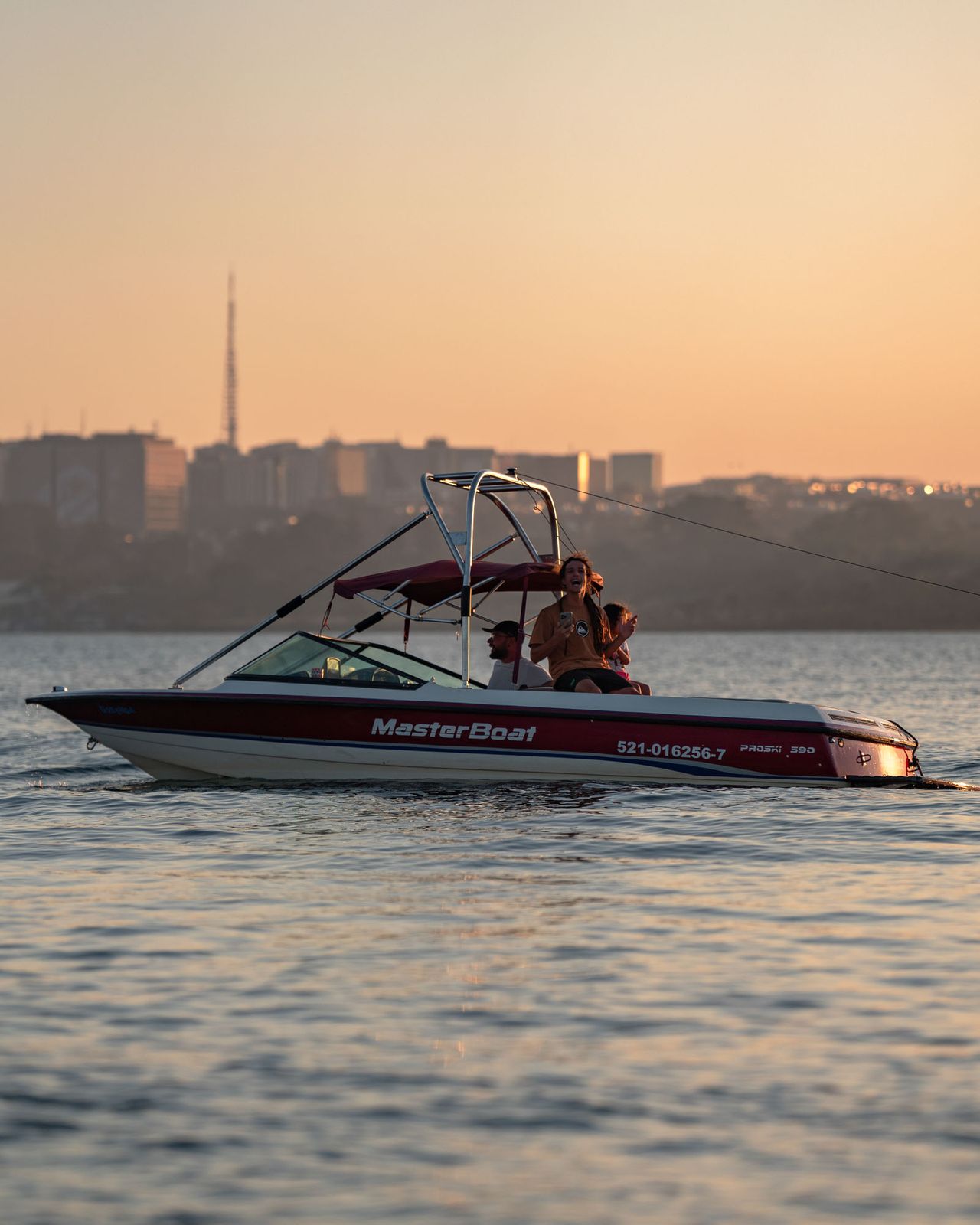 Lancha no Lago Paranoá com a skyline de Brasília e a Torre de TV ao fundo, no pôr do sol